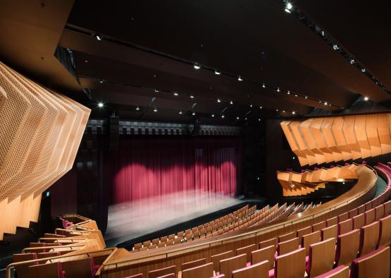 a theater with red curtains and wooden seats