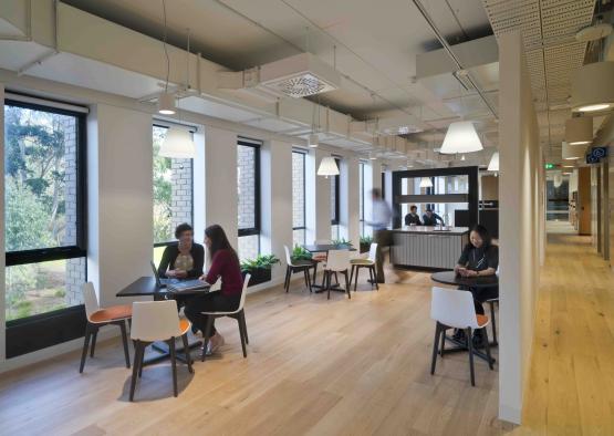 people sitting at tables in a room with windows