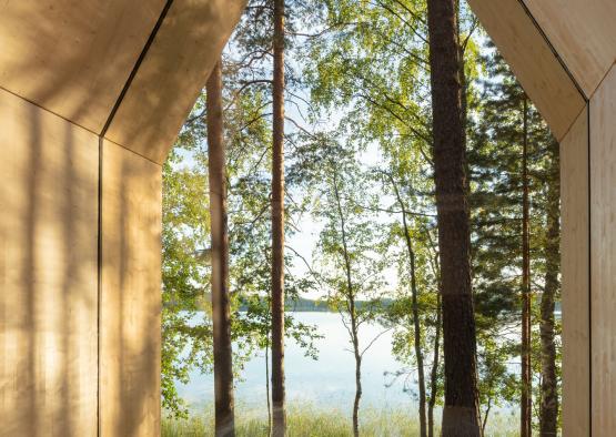 a bed with pillows and a view of trees through a window
