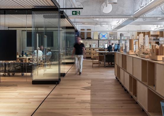 a man walking in a room with glass walls and tables