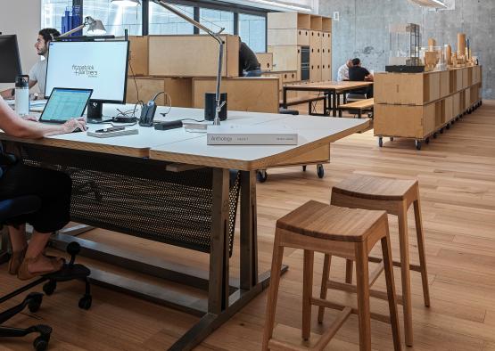 a desk with a computer and a stool in a room with boxes