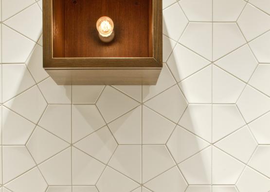 a light bulb in a box on a white tile wall