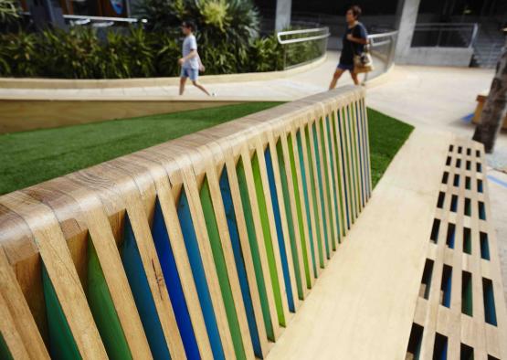 a wooden bench with a couple people walking