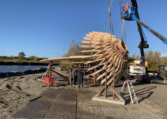 a group of people standing next to a large wooden structure