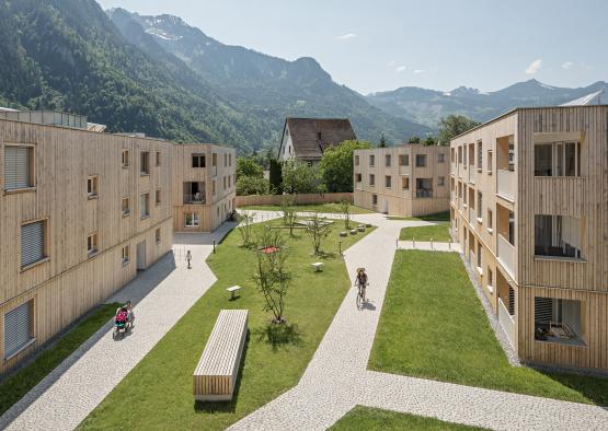 a group of buildings with a path and a group of people riding bikes