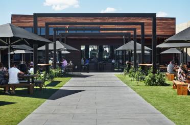 a walkway with tables and umbrellas in front of a building