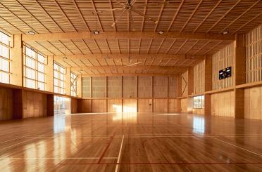 a large indoor gym with a basketball court and a ceiling fan